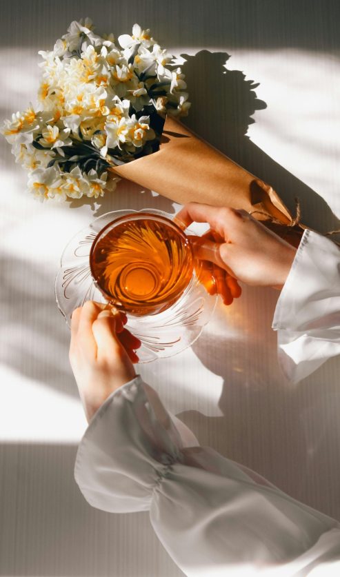 Žena drži šalicu biljnog čaja uz prozor kao prirodna podrška kod tjeskobe i stresa