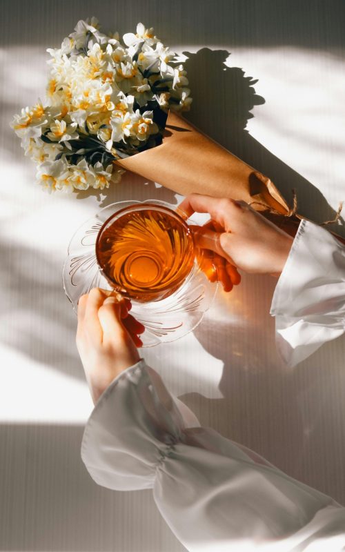 Žena drži šalicu biljnog čaja uz prozor kao prirodna podrška kod tjeskobe i stresa