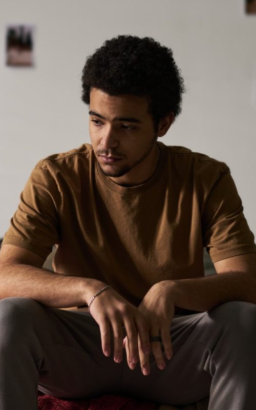 Mladić sjedi sam u sobi uz prozor, simbol izolacije i hikikomori sindroma