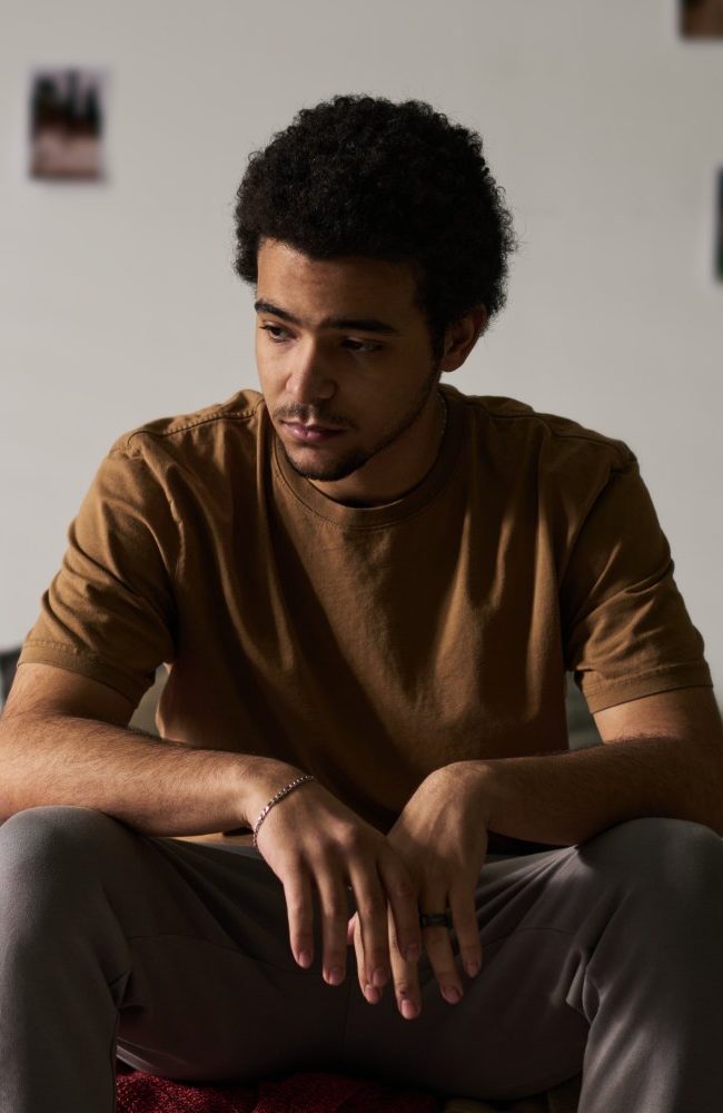 Mladić sjedi sam u sobi uz prozor, simbol izolacije i hikikomori sindroma