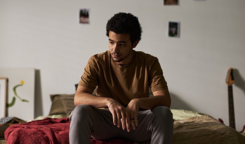 Mladić sjedi sam u sobi uz prozor, simbol izolacije i hikikomori sindroma