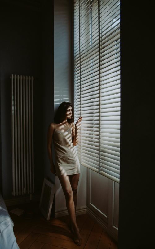 žena stoji uz prozor i gleda van osjećaj unutarnjeg nemira i tišine
