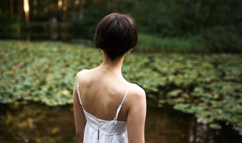 žena stoji uz vodu u prirodi, miran trenutak povezanosti s okolinom