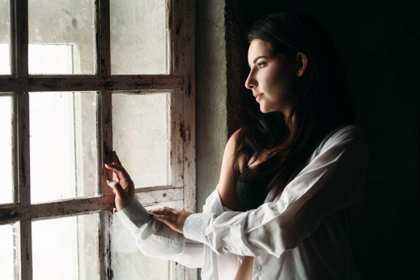 žena zamišljeno sjedi uz prozor u trenutku mentalnog preopterećenja