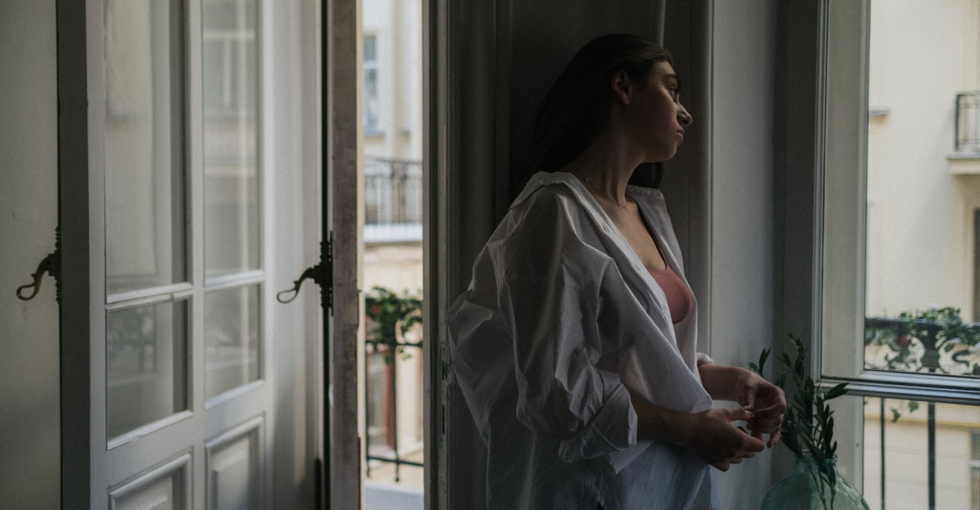 Žena stoji uz otvoren prozor tijekom toplinskog vala pokušavajući pronaći osvježenje u vrućem ljetnom danu