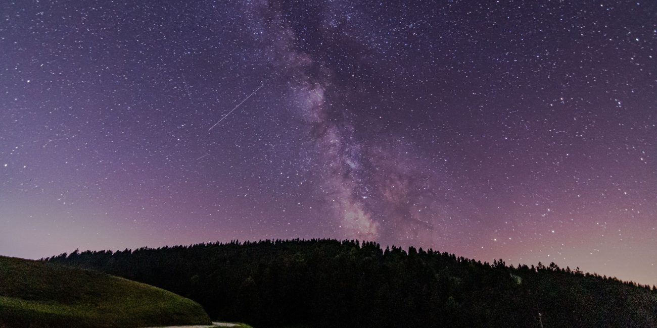 Perzeidi na noćnom nebu iznad planinskog krajolika tijekom vedre kolovoške noći.